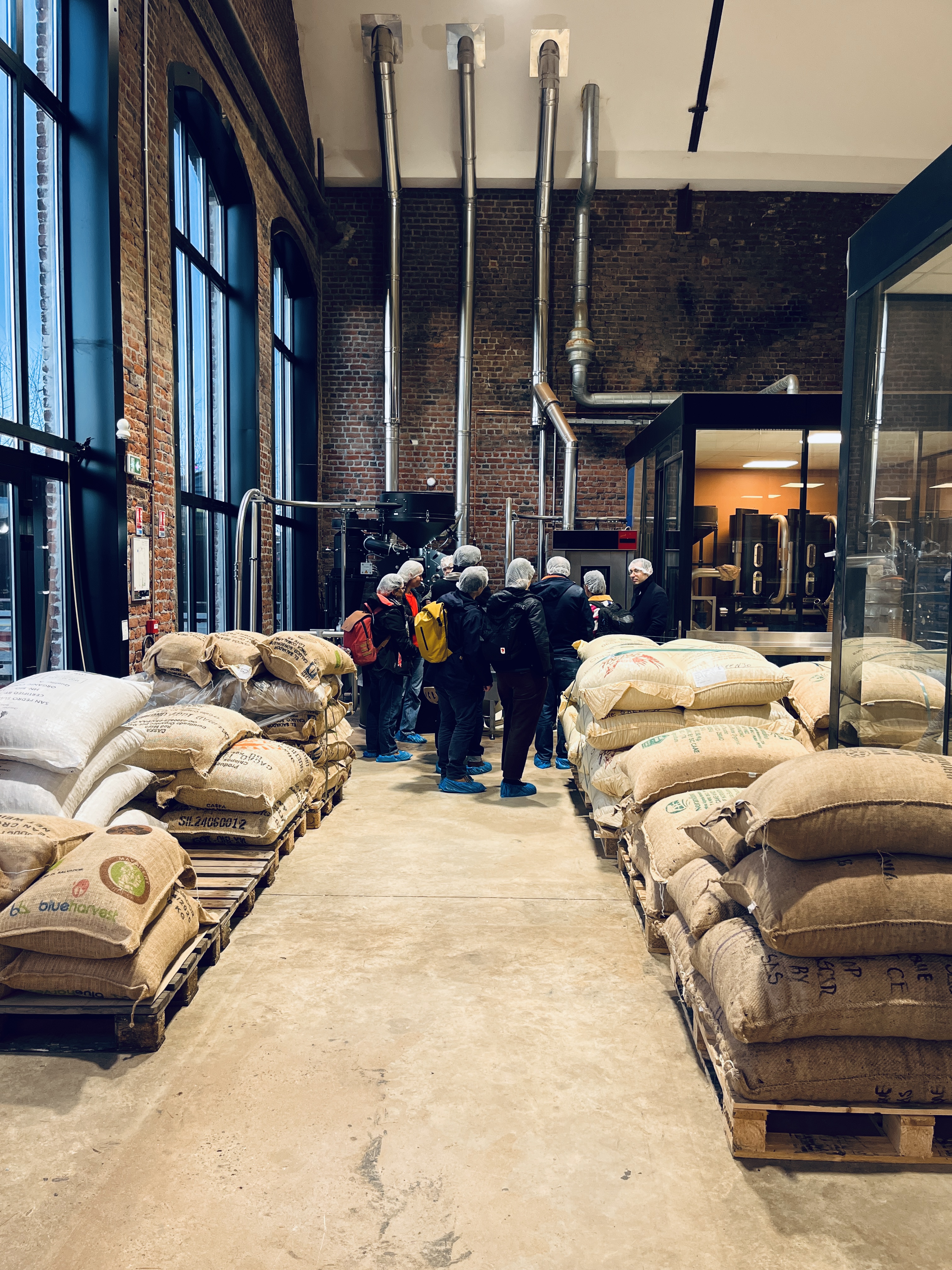 Groupe en visite guidée entre les sacs de cacao et les machines de la Manufacture Encuentro.
