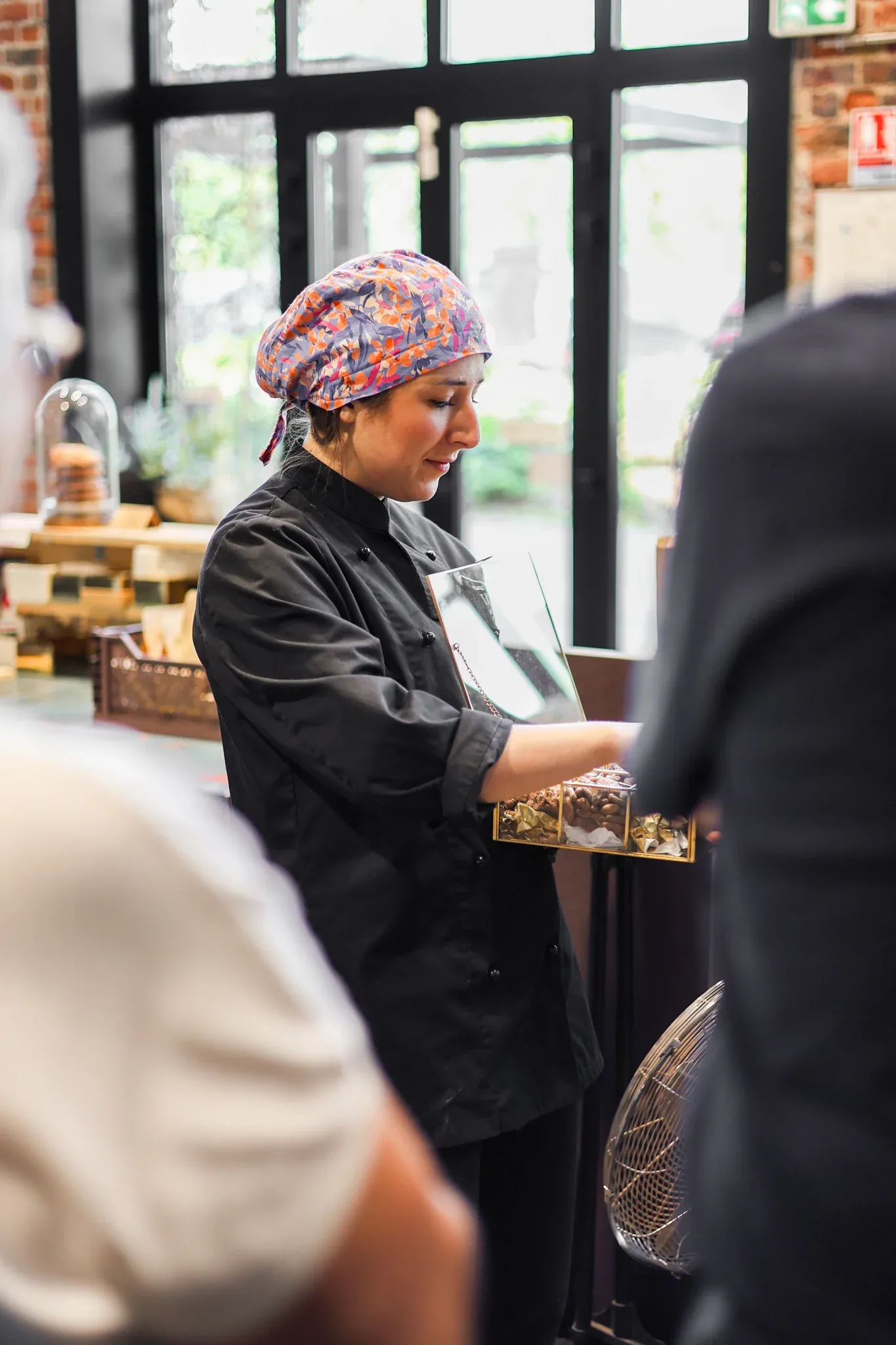 Présentation du cacao aux visiteurs par une membre de l’équipe de la Manufacture Encuentro, tenant un coffret pédagogique.